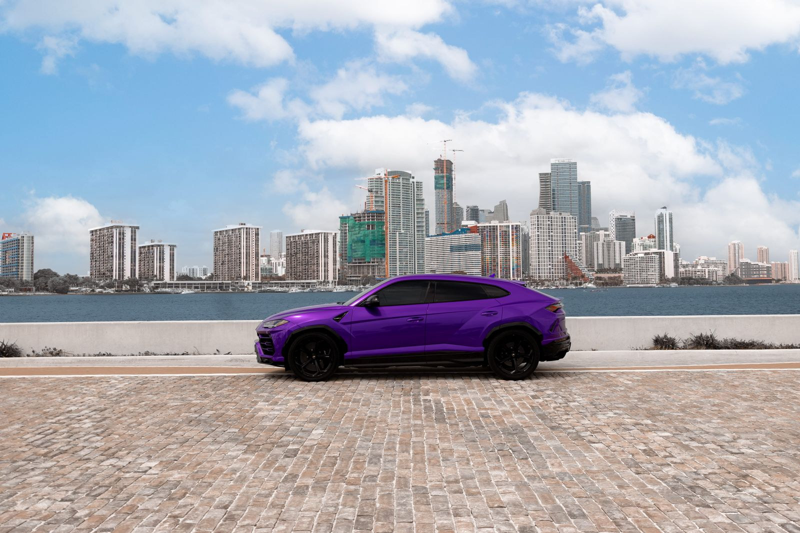 Purple Lamborghini Urus against the Miami skyline